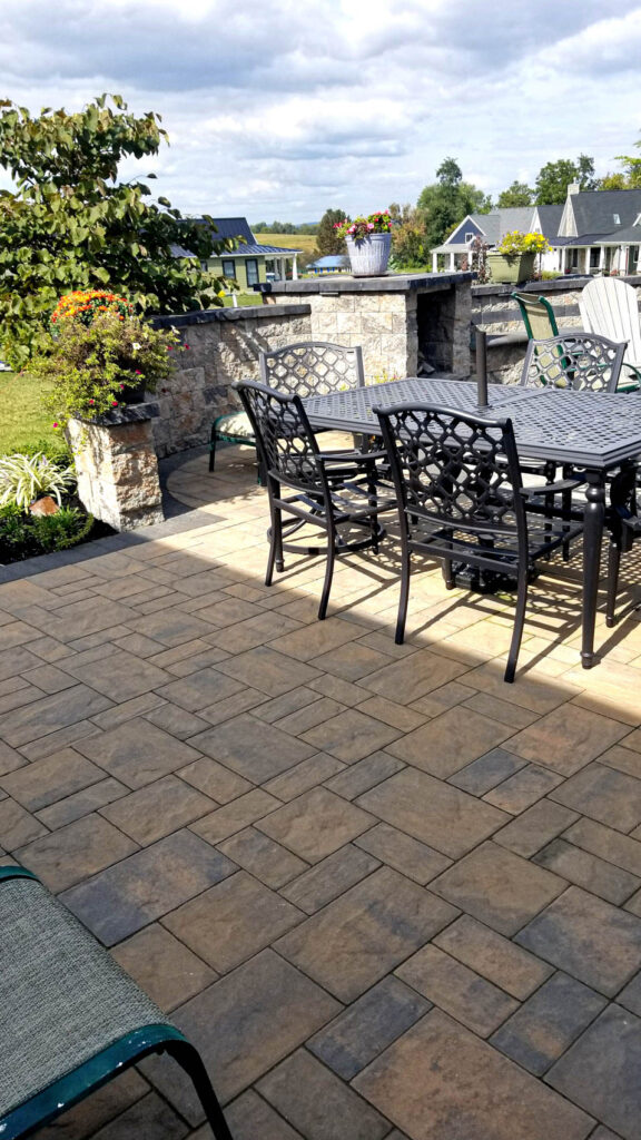 Patio area featuring a stone wall, black metal furniture, and vibrant potted plants, showcasing a safe and aesthetically pleasing outdoor space transformed by ProLawn Landscaping for client Sandra Maloney in Boiling Springs, PA.